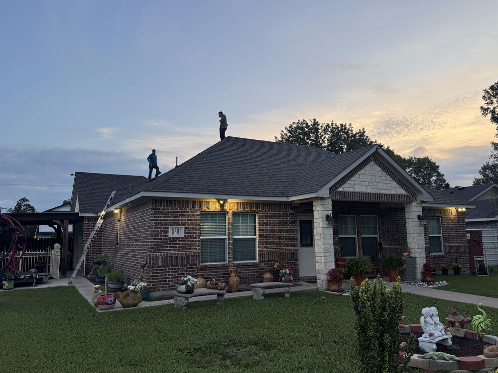 Two crew members working on roof ridge at dusk