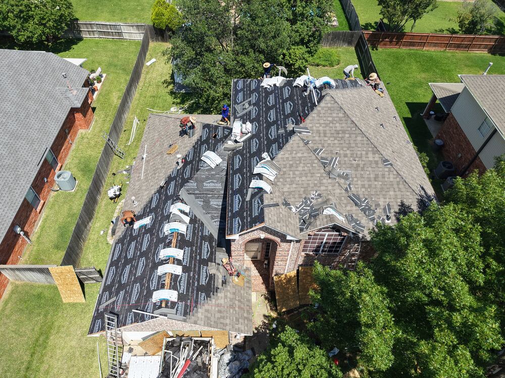 Aerial view of roof mid-installation with underlayment and crew